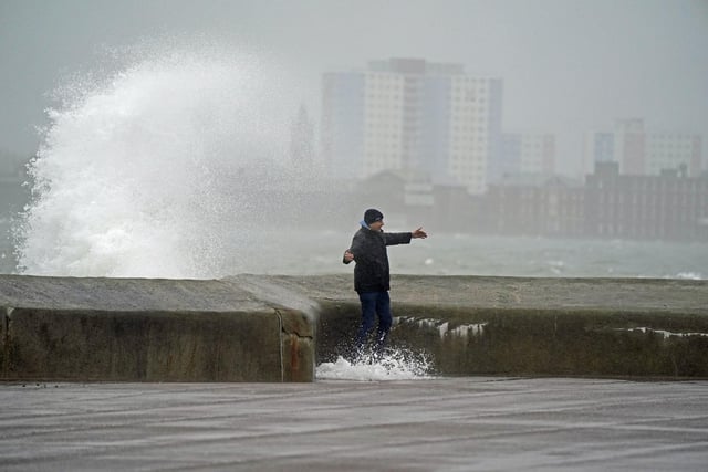 A pedestrian feels the strength of the wind as waves crash against the seafront in Southsea as Storm Barra hit. Picture: Andrew Matthews/PA Wire