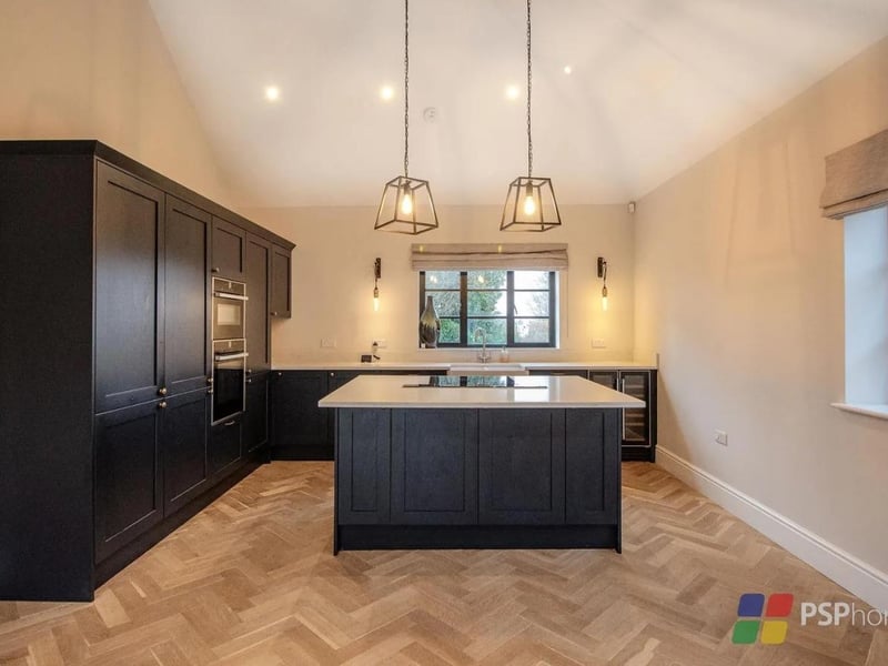 The kitchen is shaker-style with a range of wall and base units, as well as white Quartz worktops and integrated Neff appliances