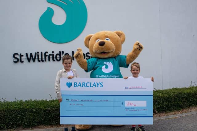 Jacob (left) and Arlo present the money to Wilfie Bear..