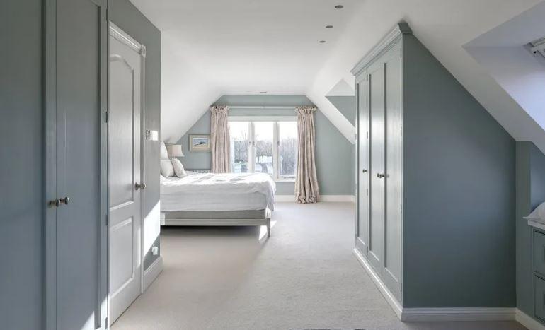 The opulent principal bedroom with views over the lake, gardens and hillsides beyond. The dressing area has several bespoke fitted wardrobes and maple cabinetry, leading to the en suite bathroom.