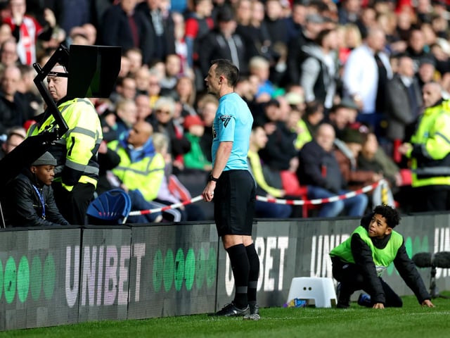 Referee Stuart Attwell checks the VAR screen for a red card for Mason Holgate of Sheffield United (not pictured), which was later given during the Premier League match between Sheffield United and Brighton & Hove Albion at Bramall Lane on February 18, 2024 in Sheffield, England. (Photo by David Rogers/Getty Images)