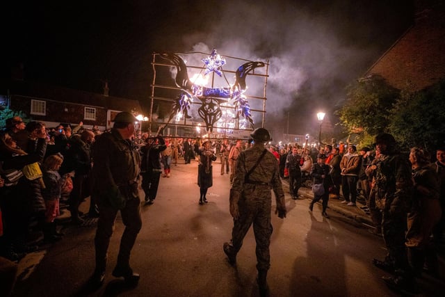 Members of the carnival society carried blazing fire banners in a series of torchlit processions to the bonfire sculpture which this year depicted a lion with its paw placed on a crown to commemorate the Queen