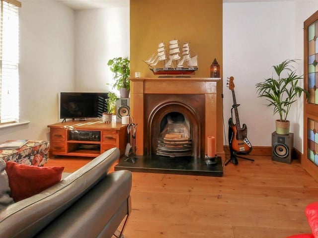 The front room has a cosy atmosphere with polished wood floors and a traditional fireplace