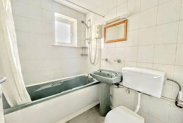 The bathroom has a toilet, basin, bath with mixer taps, overhead shower, window and an extractor fan.