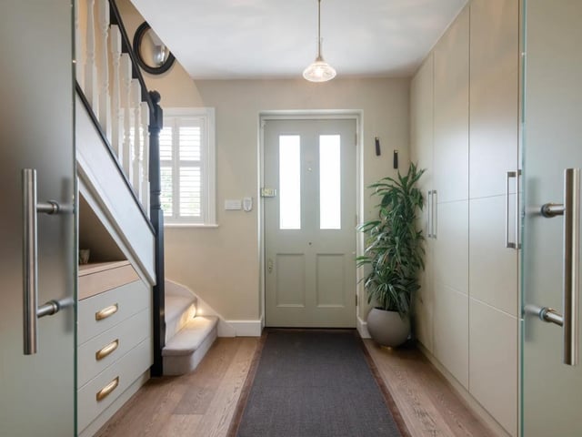 The entrance hall is fitted with bespoke floor-to-ceiling storage cupboards and an oak floor