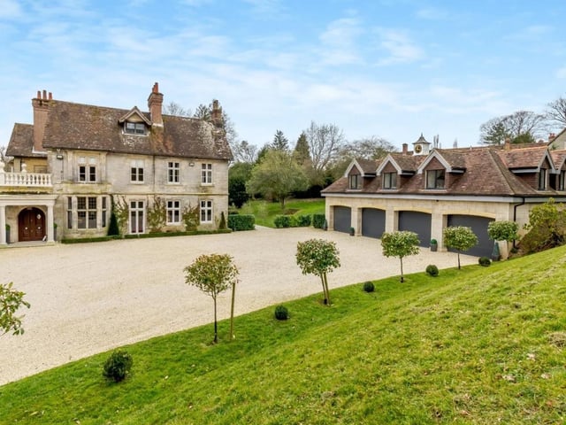 The gravel driveway leads to a large open parking area at the side of the house