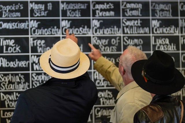 CHICHESTER, ENGLAND - AUGUST 05: Racegoers check the tipsters selections at Goodwood Racecourse on August 05, 2023 in Chichester, England. (Photo by Alan Crowhurst/Getty Images):Images from a soggy Saturday at Glorious Goodwood 2023