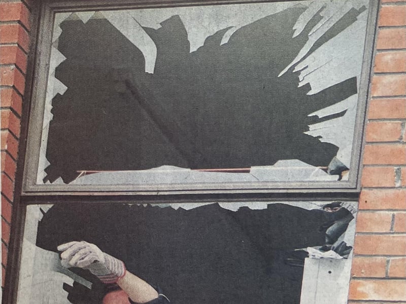 A policeman clears broken glass from a shop window