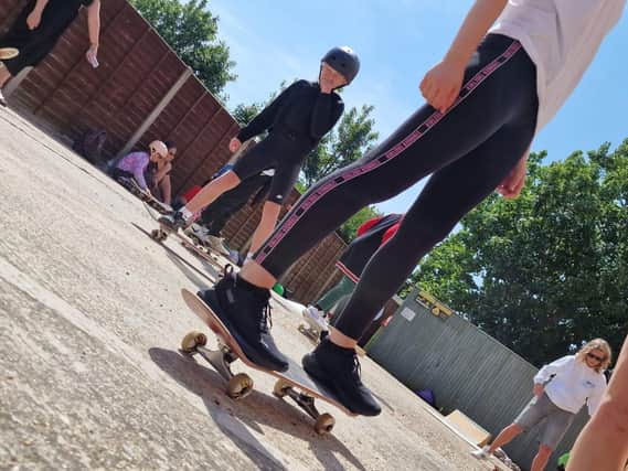 Youth Ambassadors and children attending the cafe learning skateboard skills 