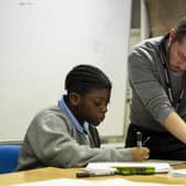 A volunteer tutor supports a pupil during a session in school
