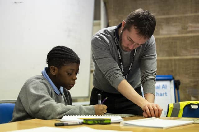 A volunteer tutor supports a pupil during a session in school
