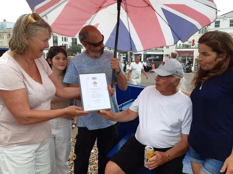 Rita Garner presents Norman Bashford with a certificate marking three generations of fishing in Worthing
