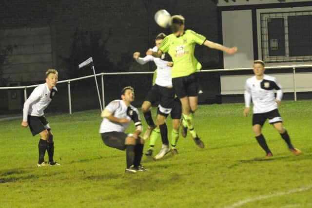 A Ringmer player gets his head to a ball into Bexhill United's penalty area.