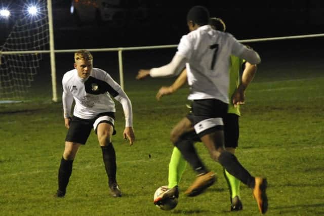 Bexhill United defender Lewis McGuigan stands in the way of a Ringmer opponent.