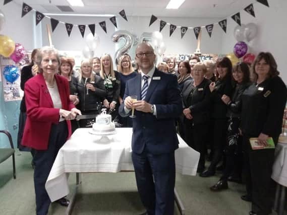 Sadie Marks cuts the 25th anniversary cake with manager Steve James, watched by staff who have worked with M&S for 25 years or more
