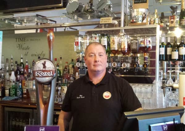 Mark Archer behind the bar where the charity boxes were ripped off