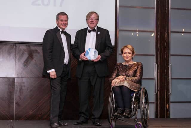 Littlehampton Shopmobility trustee Alan Gammon, centre, receives his individual special recognition award from the British Healthcare Trades Association