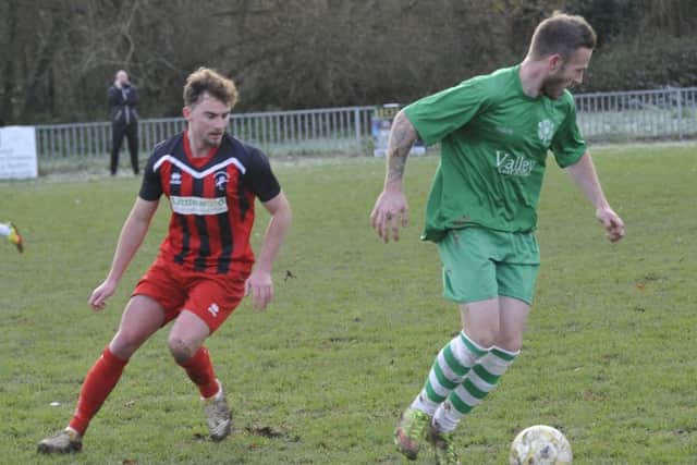 A Hollington United player closes down the Rustington man in possession.