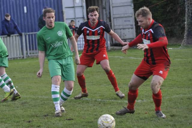 Two Hollington United players close down a Rustington opponent.