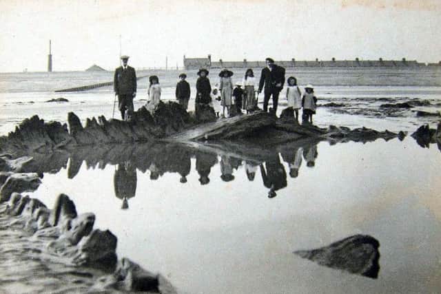 This 1912 photograph shows curious observers standing on the remains of the timber hull of the Amsterdam on Bulverhythe beach. The outline of the ship can still be seen at low tide.