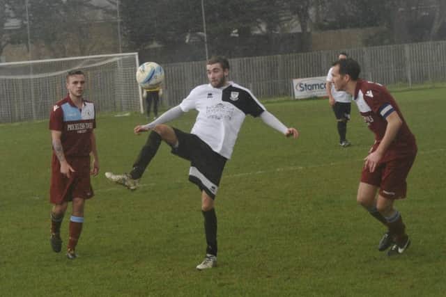 Bexhill United midfielder Nathan Lopez shapes to volley a bouncing ball as Little Common captain Lewis Hole and midfielder Harry Saville look on.