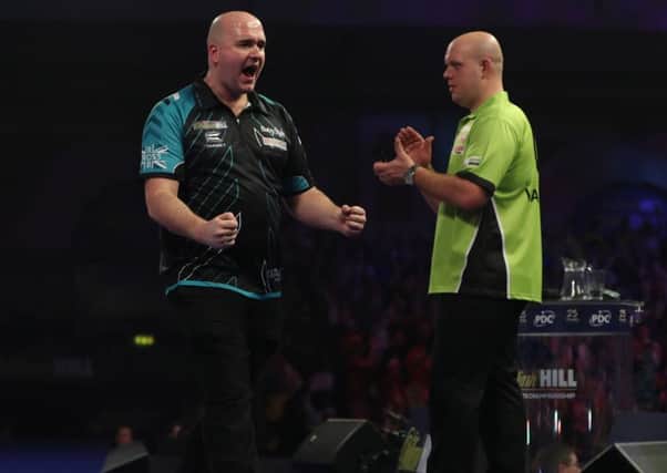 Rob Cross celebrates his magnificent victory as Michael van Gerwen graciously applauds in the background. Picture courtesy Lawrence Lustig/PDC
