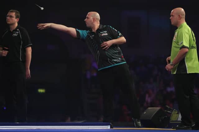 Rob Cross at the oche as Michael van Gerwen watches on. Picture courtesy Lawrence Lustig/PDC