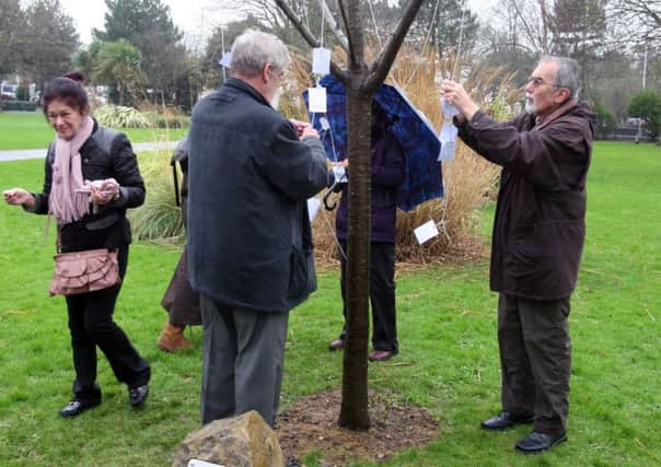 Tying messages to the Holocaust Memorial Tree in Beach House Park, Worthing, as part of last year's service. Photo by Derek Martin DM1612529a