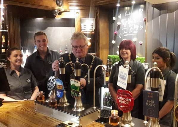 Town mayor councillor James Knight pulling the first pint next to staff