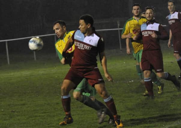 Little Common midfielder Wes Tate seeks to escape the clutches of a Hailsham Town defender at The Beaconsfield on Tuesday night. Pictures by Simon Newstead