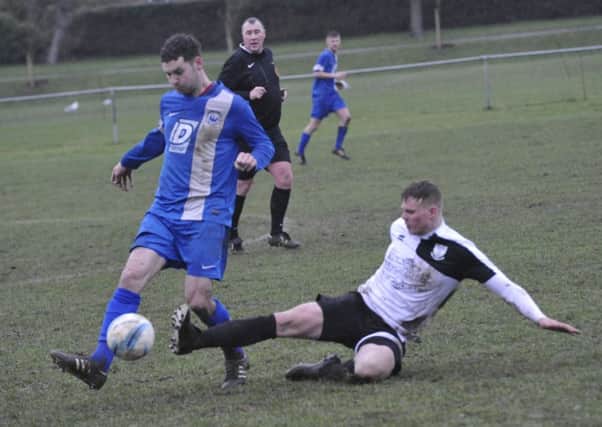 Bexhill United defender Lewis McGuigan slides in to a tackle. Pictures by Simon Newstead