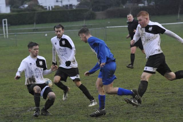 Bexhill midfielder Kyle Holden blocks the path of a Storrington opponent with Nathan Lopez and Zack McEniry in support.