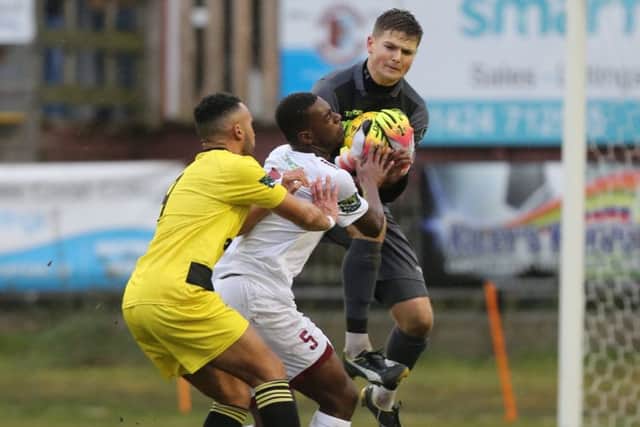 Hastings United goalkeeper Charlie Horlock gathers the ball as Sinnkaye Christie is pushed into him against Ashford United on Saturday. Picture courtesy Scott White