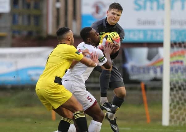 Hastings United goalkeeper Charlie Horlock gathers the ball as Sinnkaye Christie is pushed into him against Ashford United on Saturday. Picture courtesy Scott White
