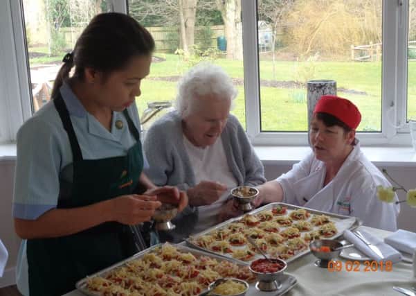 A Westlake House care home resident enjoying making homemade pizzas to makr National Pizza Day SUS-180214-093916001