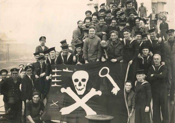 Leading Seaman Tom Parke (furthest right holding flag) with his crewmates after their 'hat-trick' submarine sinking