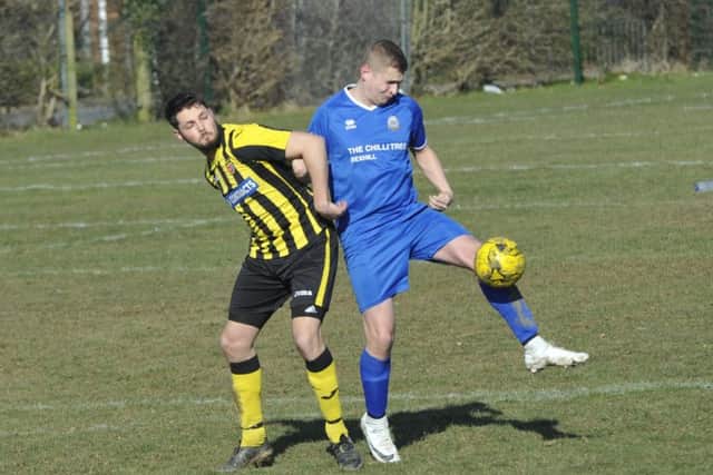A Bexhill Rovers defender holds off a Catsfield forward at Gunters Lane.
