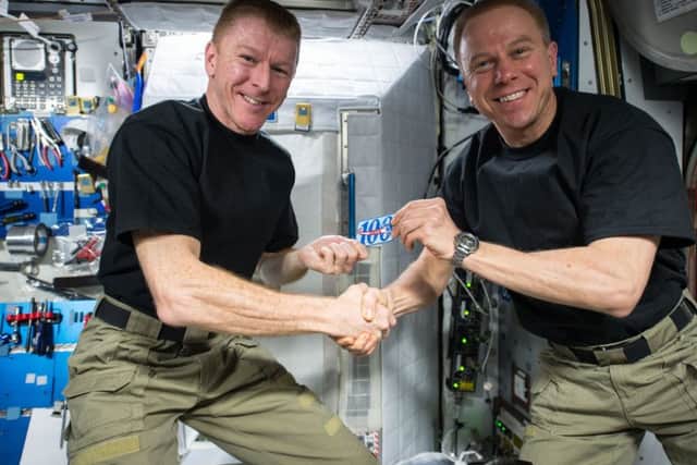 NASA astronaut Tim Kopra (right) presents Tim Peake (left) with a patch to commemorate his 100th day in space