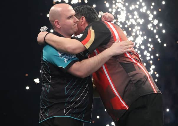 Rob Cross is congratulated by opponent Mensur Suljovic after his 7-2 victory. Picture courtesy Lawrence Lustig/PDC
