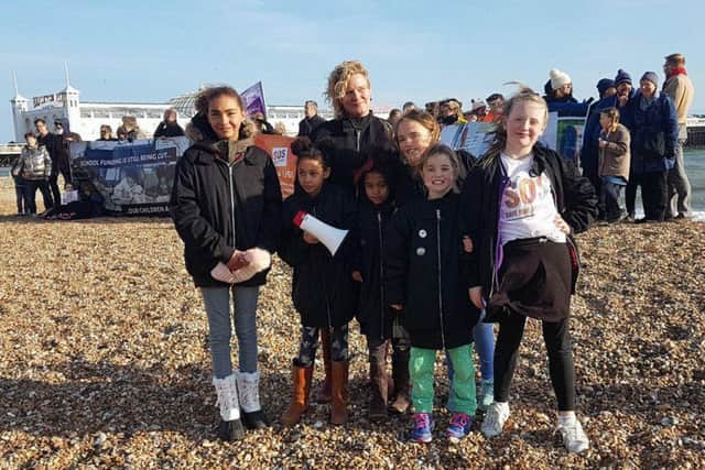 Campaigner Alison Ali with her two children and their friends, in front of the banner which was held up by protesters at Brighton beach yesterday