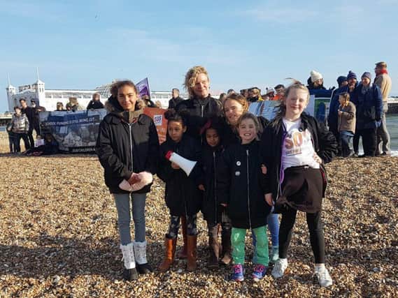 Campaigner Alison Ali with her two children and their friends, in front of the banner which was held up by protesters at Brighton beach yesterday