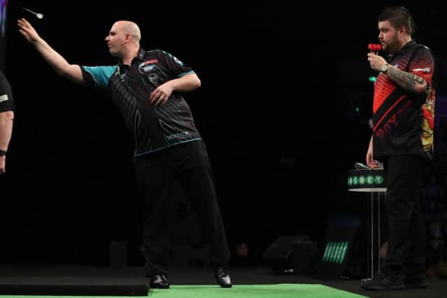 Rob Cross at the oche as Michael Smith looks on. Picture courtesy Lawrence Lustig/PDC