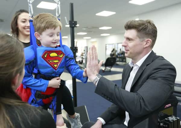 Matthew Reeve high-fiving Jasper, 5, who has greatly benefitted from treatment at Neurokinex