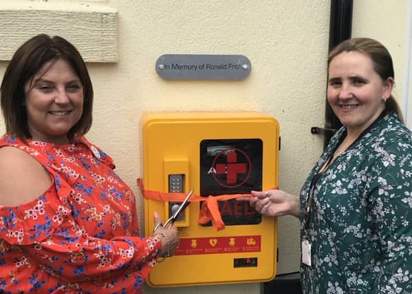 Willow Lodge Care Home's manager and deputy manager cutting the ribbon for the defibrillator