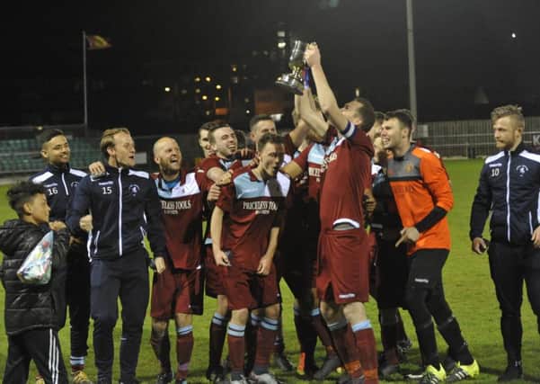 Little Common captain Lewis Hole raises the Division One Challenge Cup in front of his jubilant team-mates. Pictures by Simon Newstead