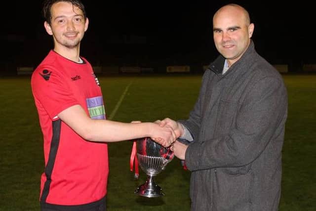 Rye Town Football Club captain Sam Henham receives the Premier Travel Challenge Cup.