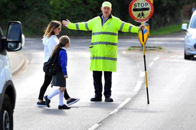 Lollipop man Mick Bassett helps Elaine Boys and her daughter Yasmin across the road