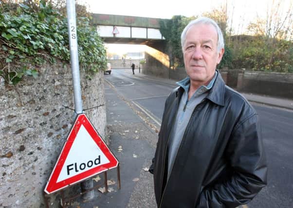 Will Flewett by a flood sign under the bridge in November 2016