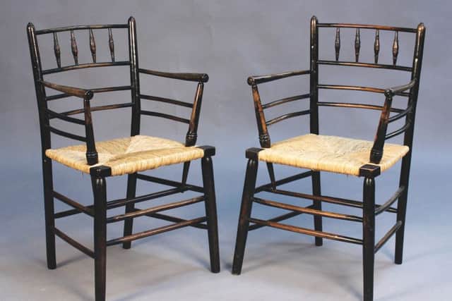 A pair of late 19th century ebonized ash Sussex armchairs by Morris & Co, with turned spindle backs above rush seats, on turned legs.