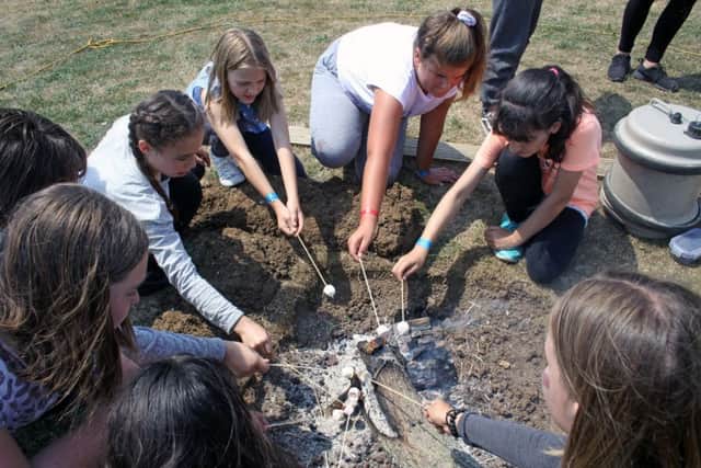 Roasting marshmallows on the fire at The Big Camp at Hove Park School SUS-181007-113408001
